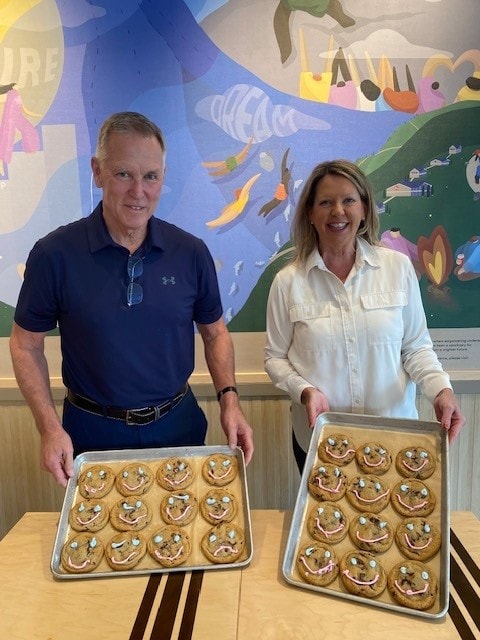 Jane Twinney holding cookies in front of colourful mural